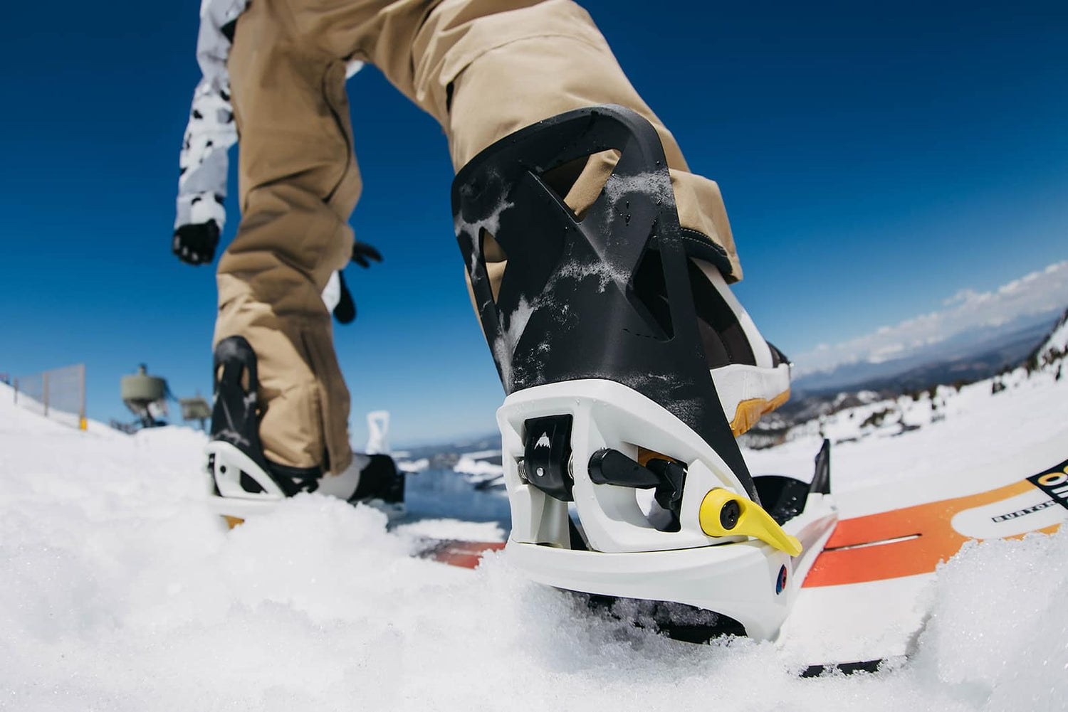 Burton binding parts availability and how to order: A wide-angle view of a Step On snowboard binding and a rider preparing to snowboard.