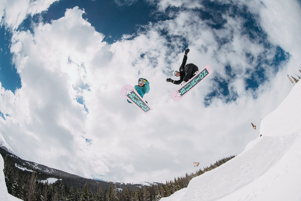 Goofy vs. Regular: Two riders getting massive air off a jump, viewed from below.