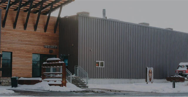Building exterior with 'Burton Custom Handmade' logo on a snowy day