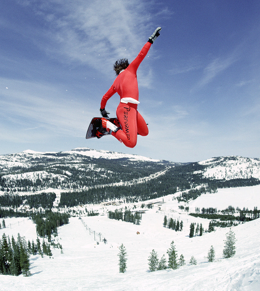 Photo of snowboarder Andy Coghlan doing a method air in a red performer body suit.