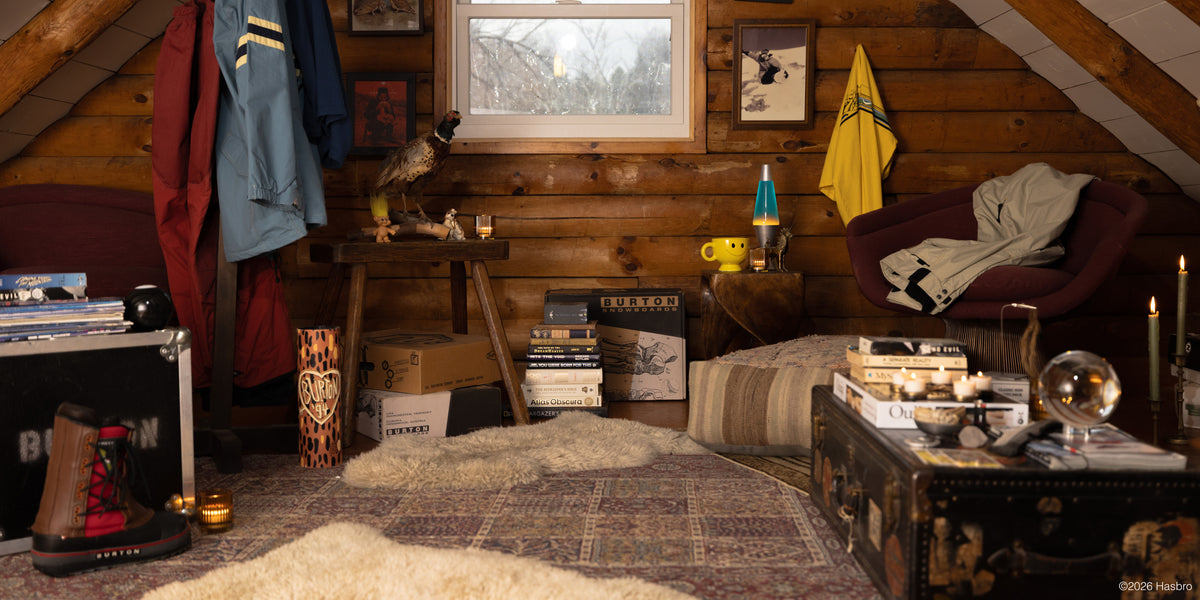Cabin setting that shows historic snowboarding gear, candles on a table, and a snowy scene outside the window