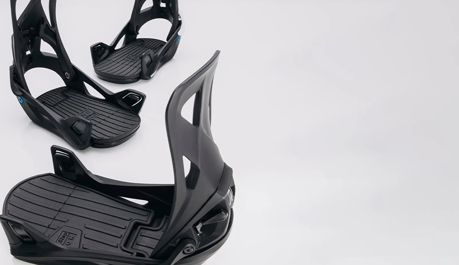 Black snowboard bindings on a light gray background