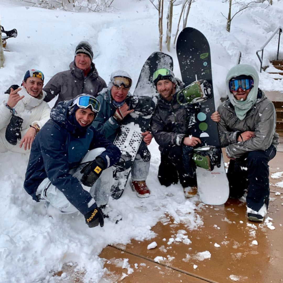 Jake poses at bottom of the mountain  with Burton Team riders, friends, and son, Timi