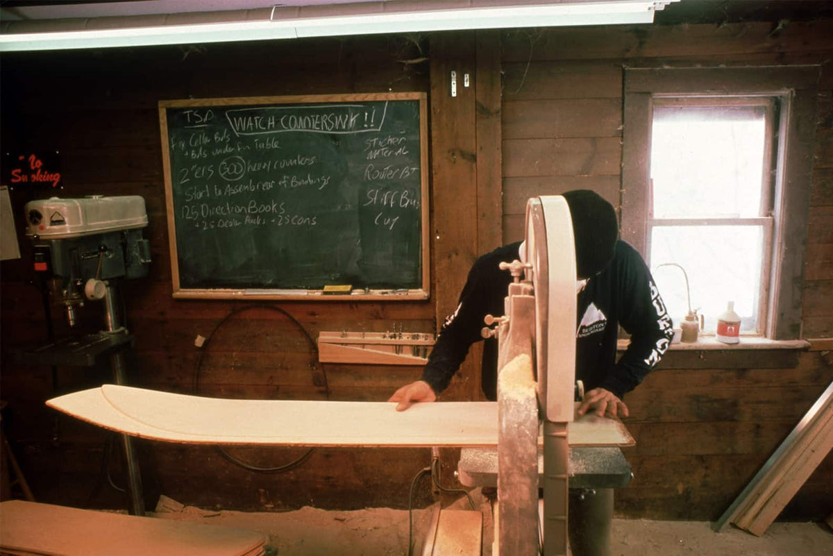 Man making snowboard design out of wood. 