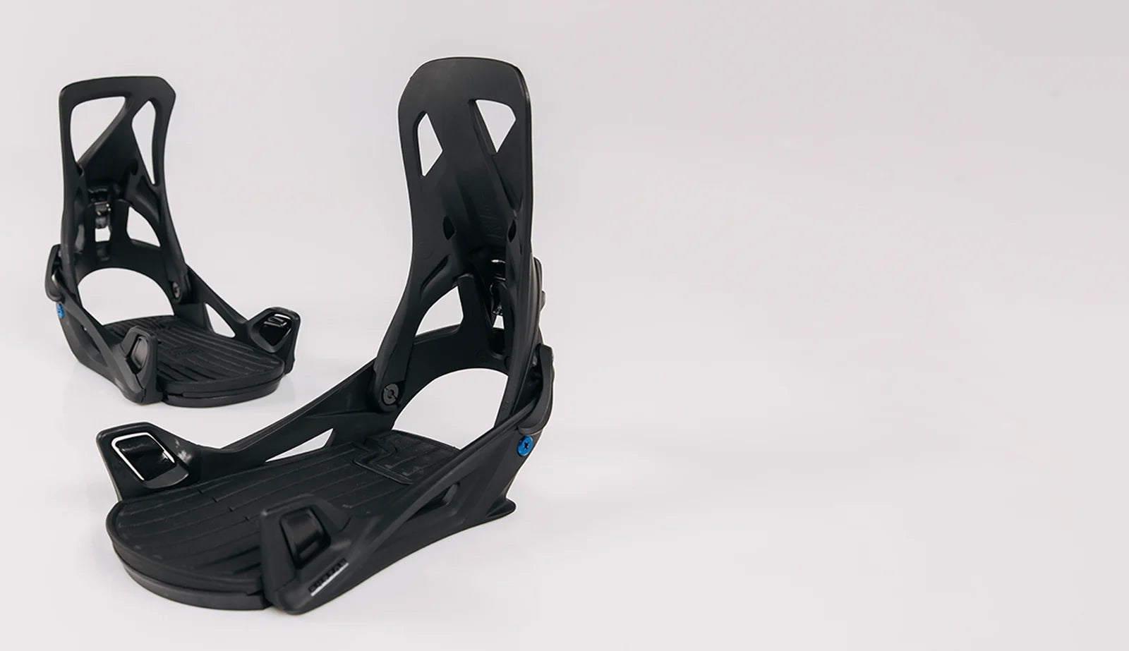Black snowboard bindings on a white background