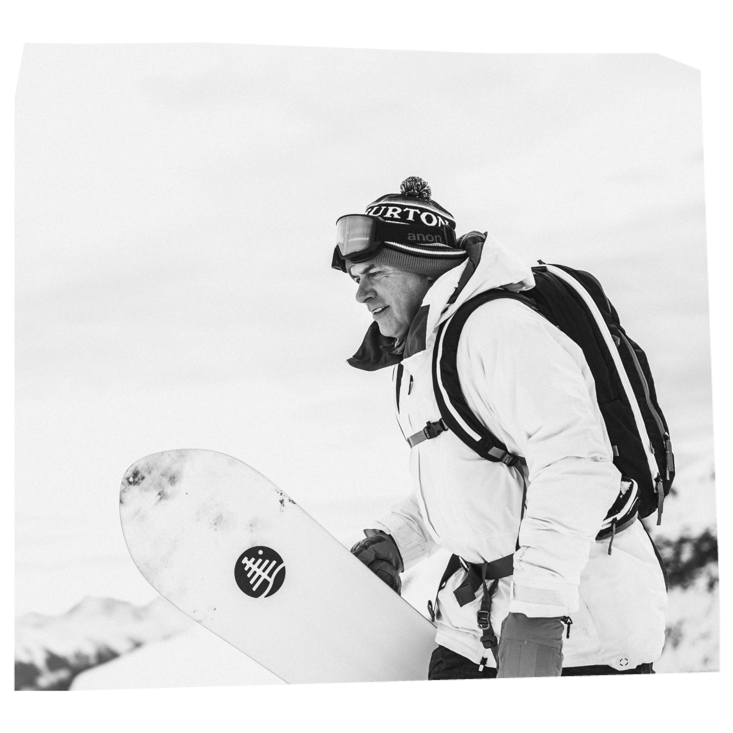 Jake Burton Carpenter hiking uphill with his snowboard