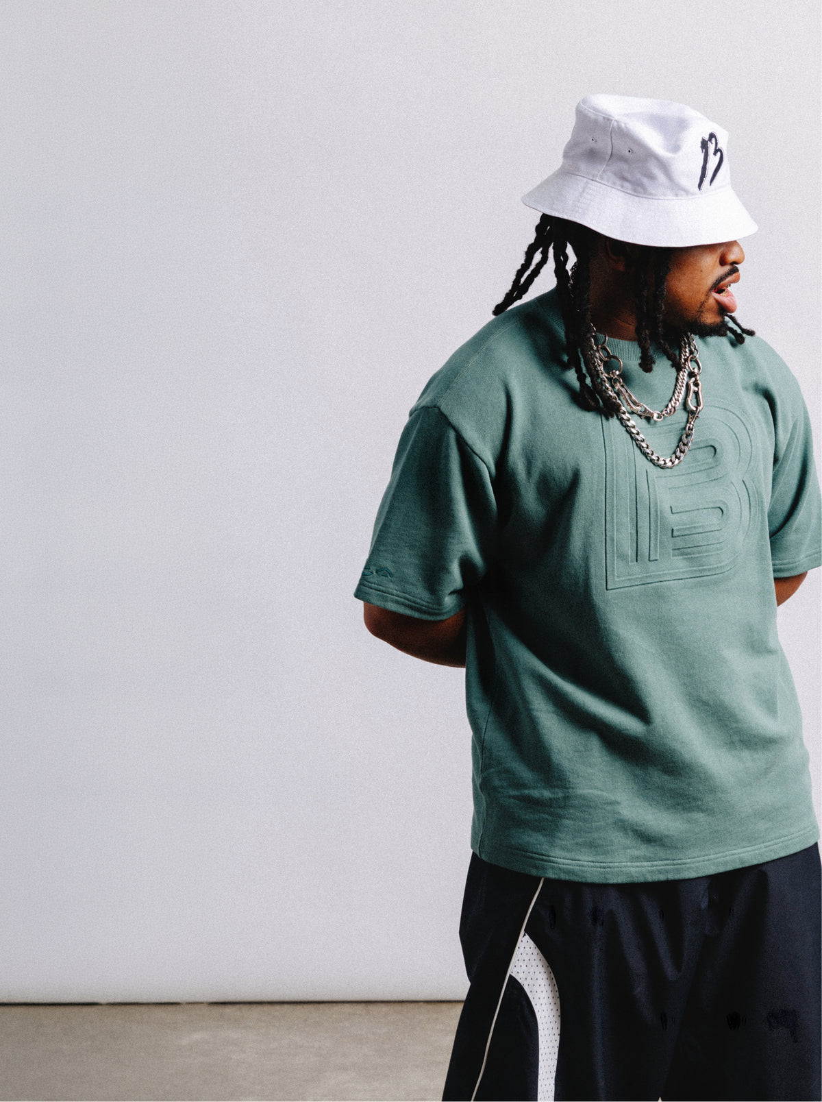 rider, zeb, modeling white Burton "B" bucket hat & embossed "B" tee in green