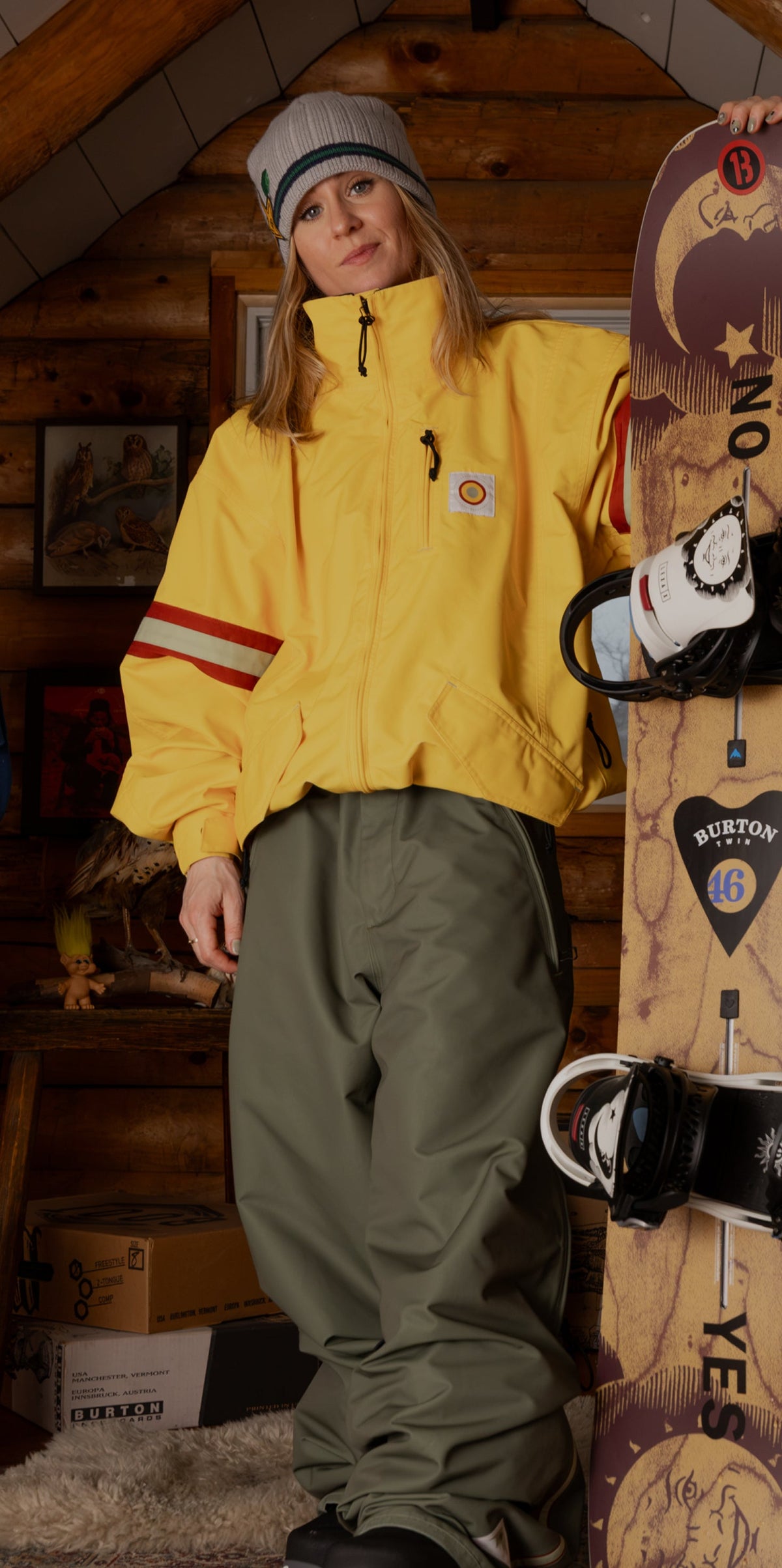 Ylfa Runarsdott holding a snowboard upright in a timber-frame attic