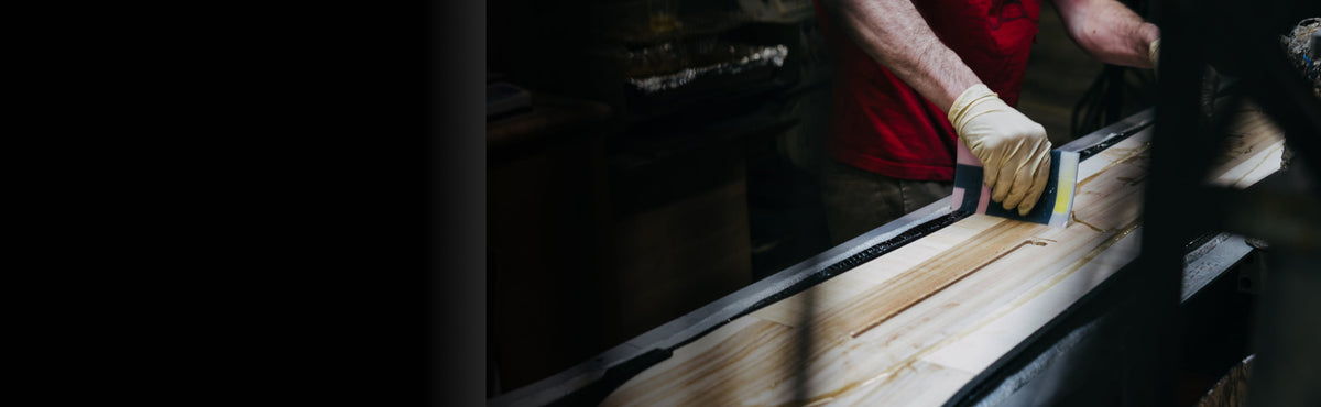 a gloved hand applying finish to a snowboard