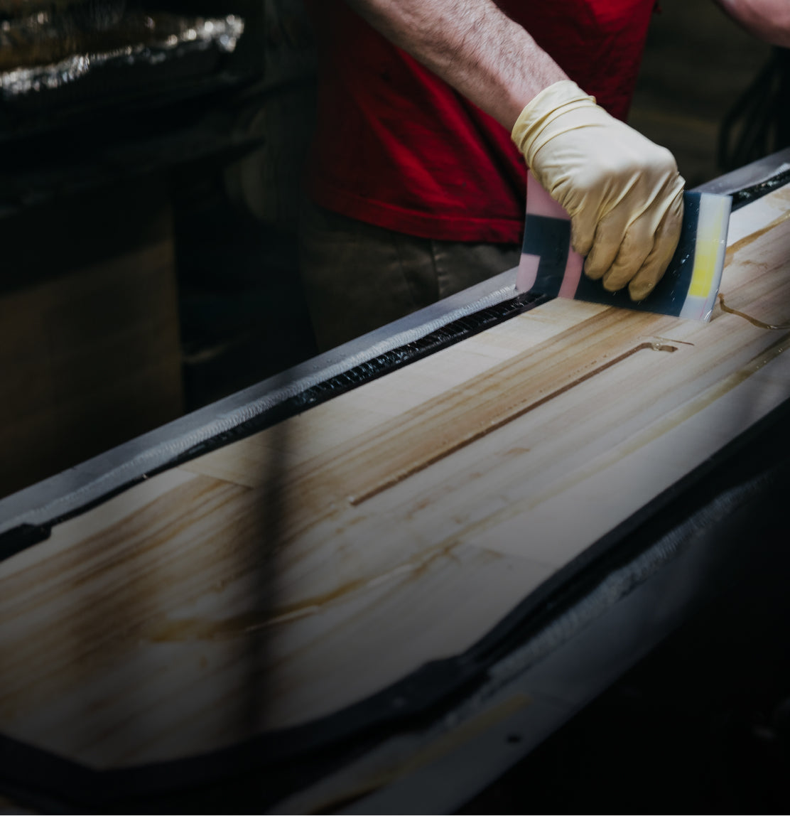 a gloved hand applying finish to a snowboard