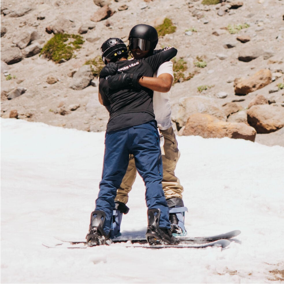 Zwei Personen auf Snowboards, die sich umarmen