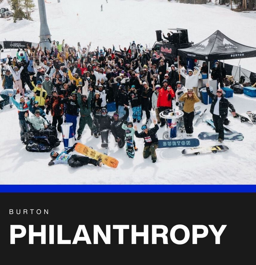 A large group of snowboarders posing for a photo on snow