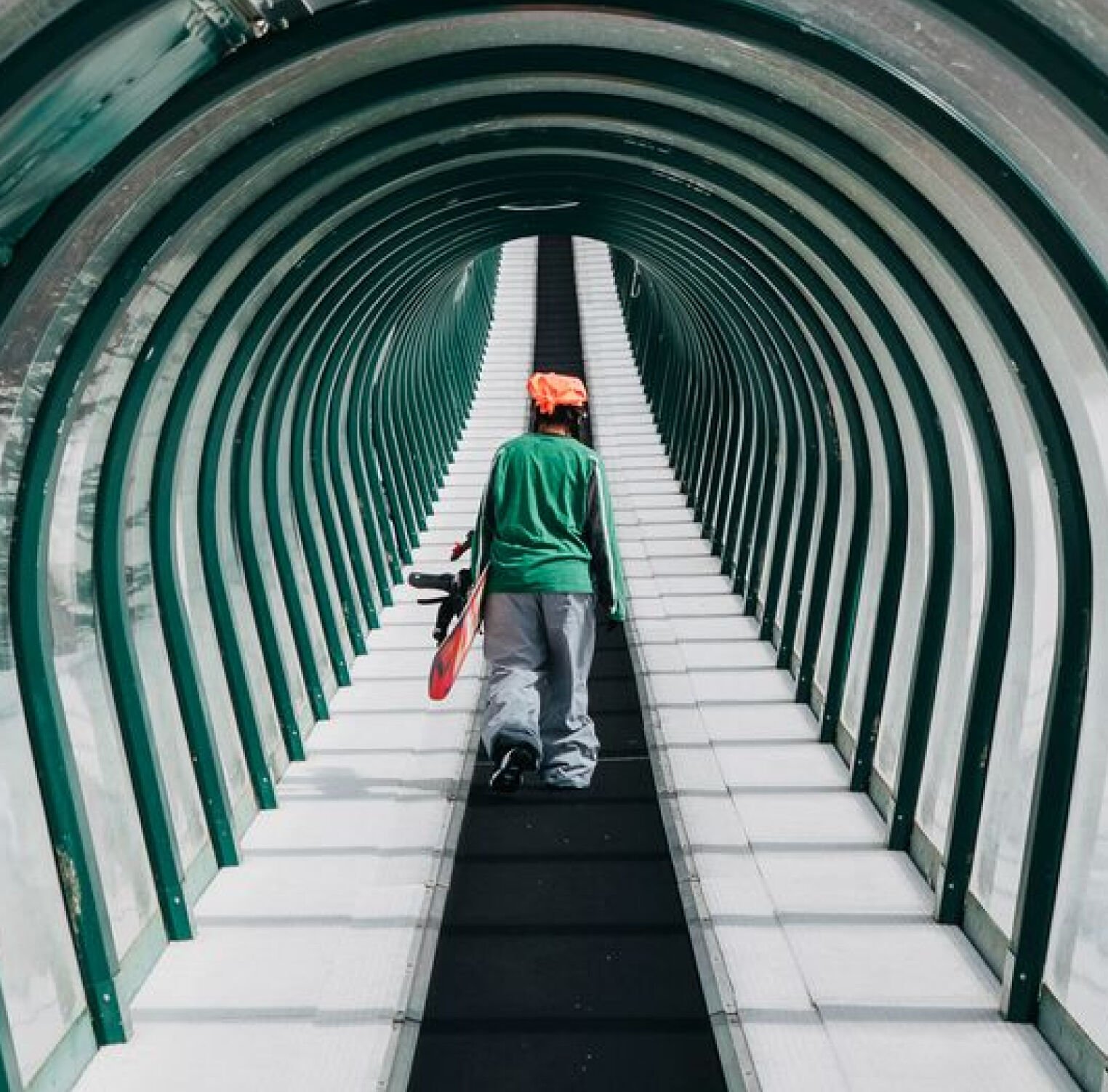 A snowboarder walking on the magic carpet at a resort